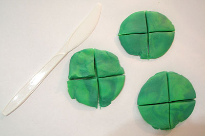 Three circular 'pancakes' made of modelling dough, each divided into four equal parts.